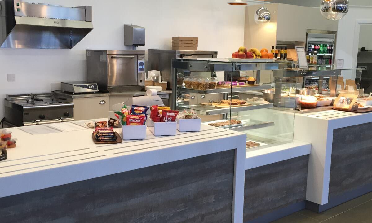 A photo of the inside of a restaurant with a counter full of food.