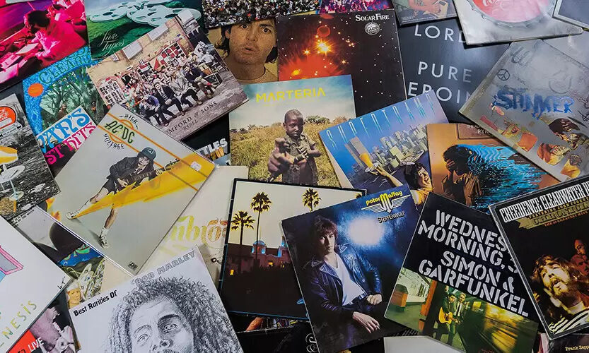 A photo showing a large number of music vinyls spread on a table.