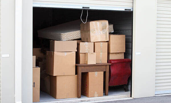 A photo showing a self-storage unit fully packed with boxes and furniture.