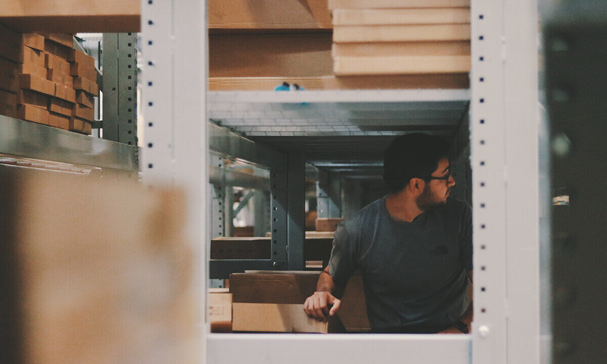 A photo showing a man inside of a workshop surrounded by cardboard boxes.