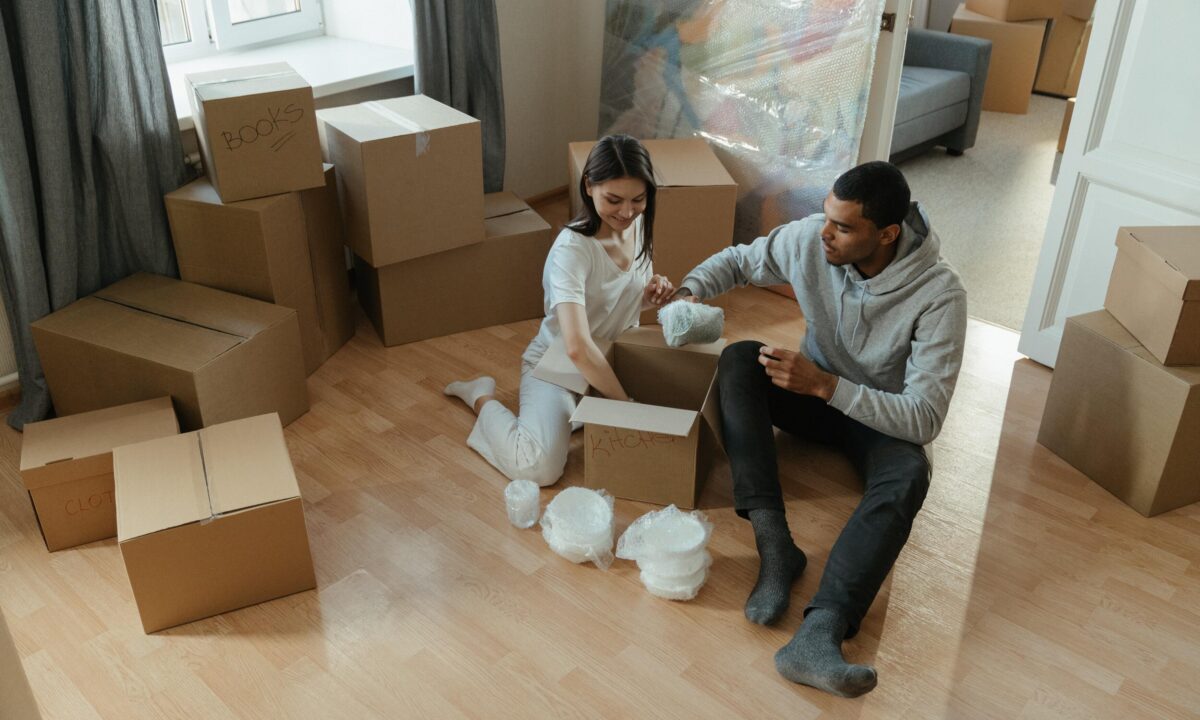 A photo showing two people packing cardboard boxes for a move.