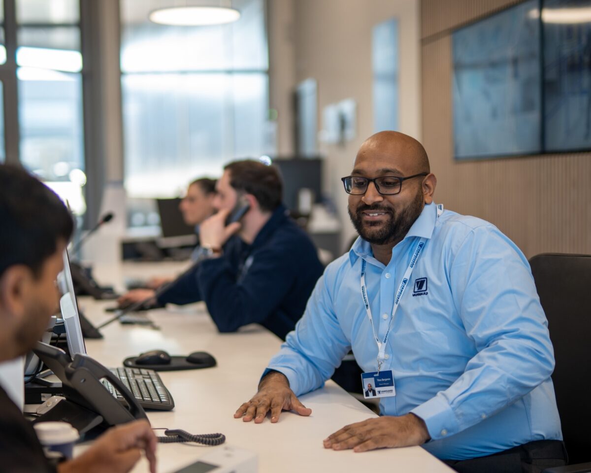 A photo of a Vanguard employee working at the reception and chatting to a customer.