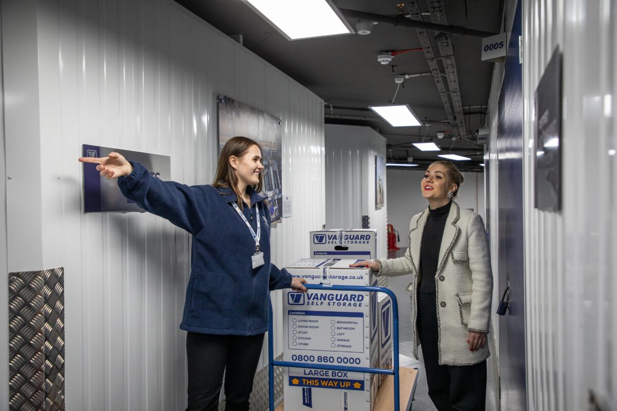A photo of a Vanguard employee helping a customer transport their belongings into their self storage unit.