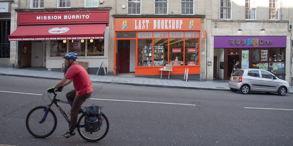 A photo of a person cycling in front of some shops in Bristol, where Vanguard have a self-storage branch.