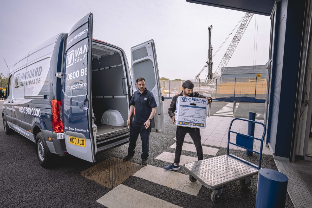 A photo showing a Vanguard employee helping a customer move boxes from a van and onto a trolley.