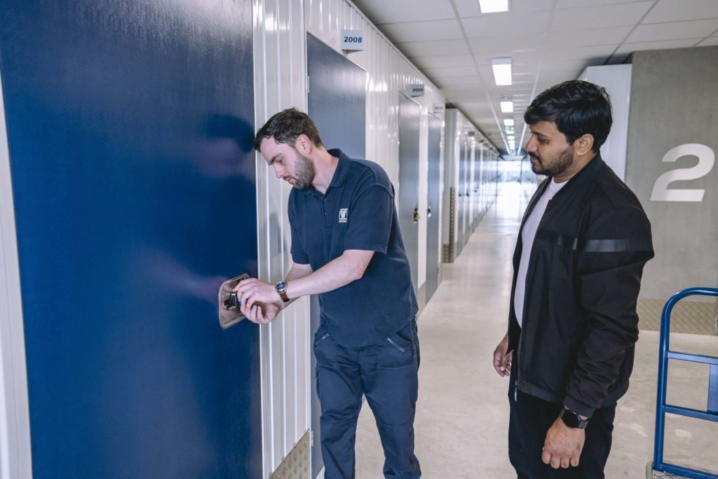 A photo showing a Vanguard employee unlocking a storage unit for a customer at one of the Vanguard Self Storage branches.