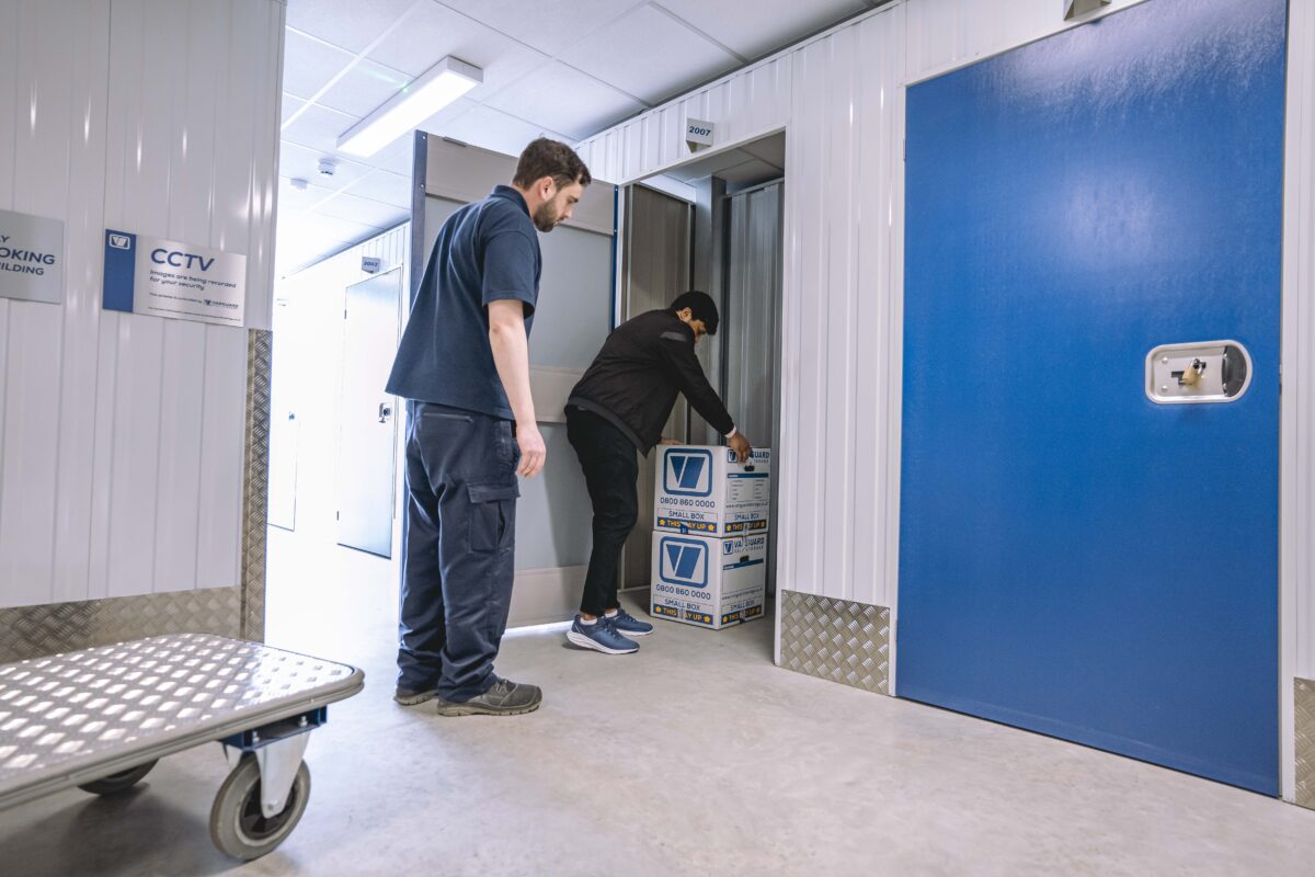 A photo showing a Vanguard employee helping a customer move Vanguard storage boxes into a self-storage unit.
