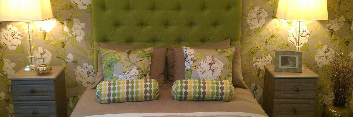 A photo showing a double bed with two bedside tables and lamps on either side.