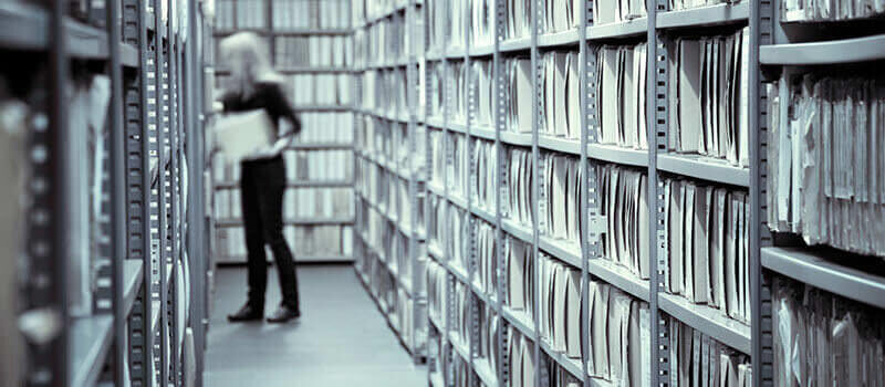 A photo showing a woman browsing files inside of a document archive.
