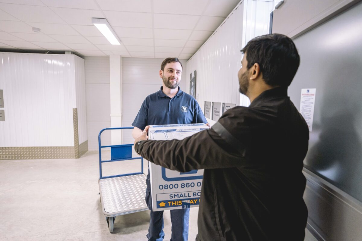 A photo showing a Vanguard employee helping a customer carry a storage box in one of the Vanguard Self Storage branches.