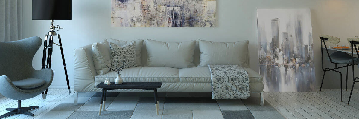 A photo of a living room featuring a sofa, an armchair and a tall lamp, with a dining table and chairs on the right.