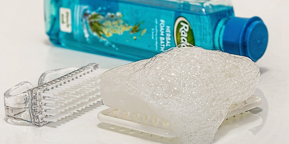 A photo showing a set of toiletries, with soap, a brush and a sponge.