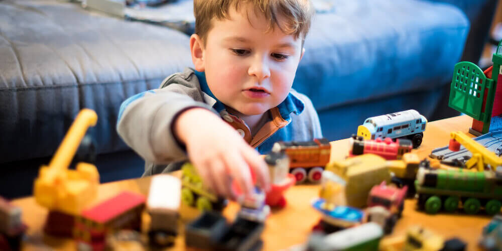 A photo showing a child playing with toys on a table.