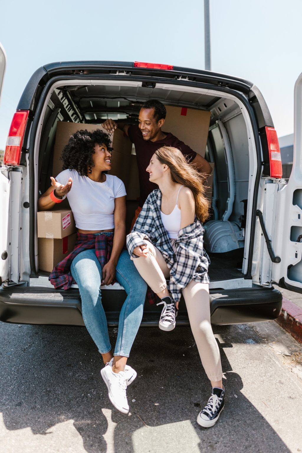 A photo showing three people standing in the back of a van.