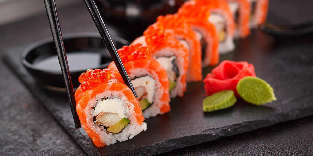 A photo showing chopsticks picking up a piece of sushi.