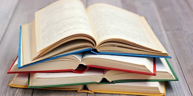 A photo showing four books open and stacked on top of each other.