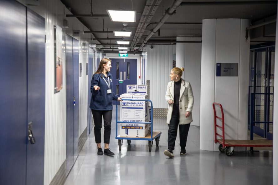 A photo showing a Vanguard employee helping a customer take some boxes into a storage unit at one of Vanguard's self storage branches.