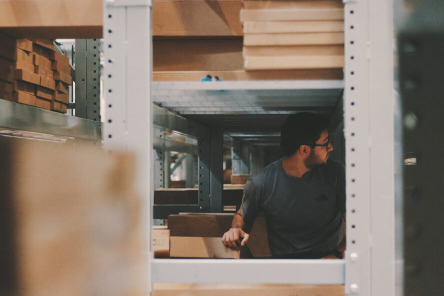 A photo showing a man inside of a workshop surrounded by cardboard boxes.